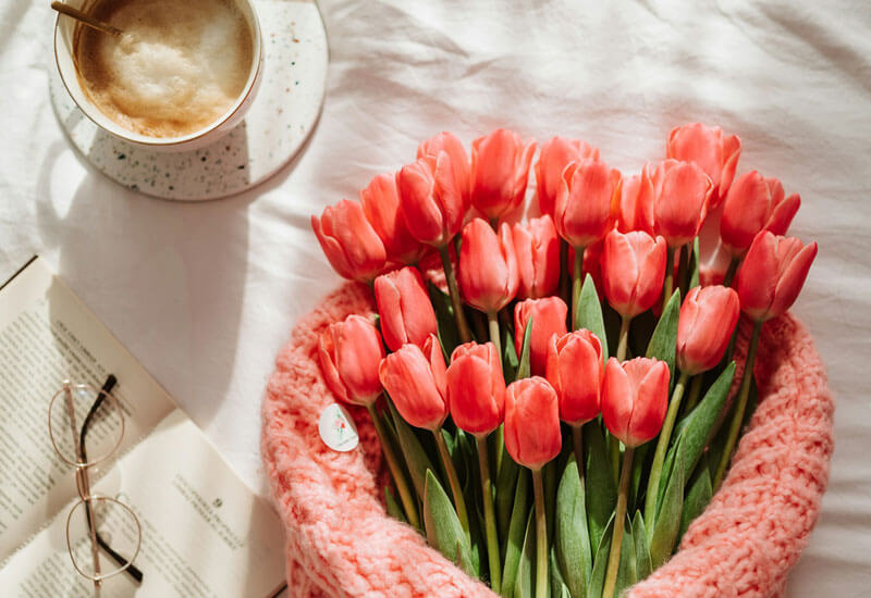 A Bouquet of Red Tulips next to a Cup of Coffee Image